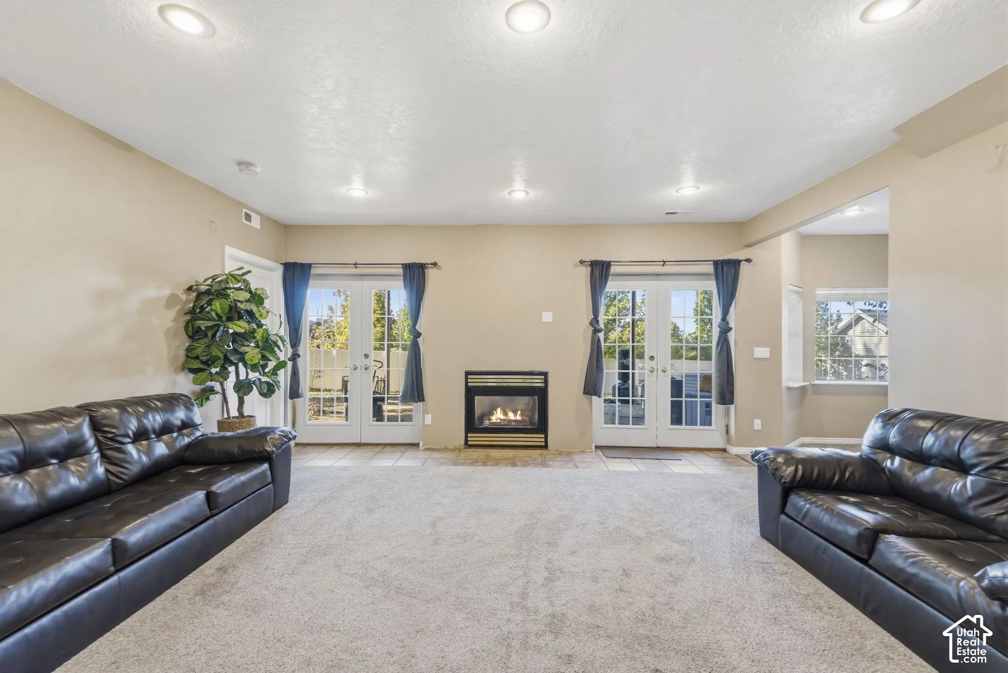 Living space featuring recessed lighting, a centered fireplace with a metallic finish, and dual sets of glass-paned doors
