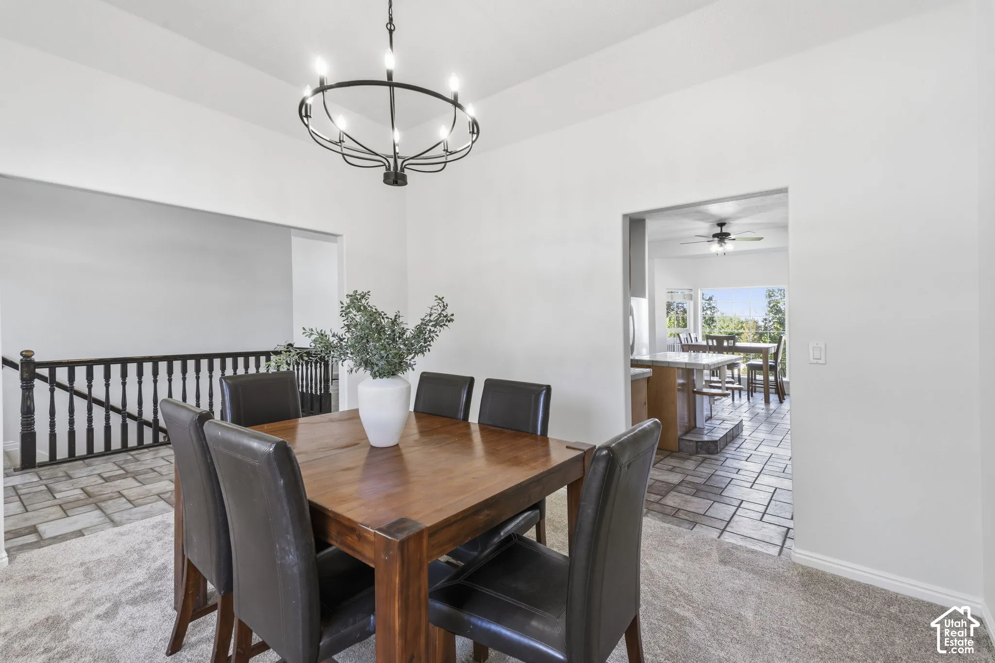 High-ceiling area featuring a black metal chandelier, dark wood-tone banister with spindles, and tile flooring