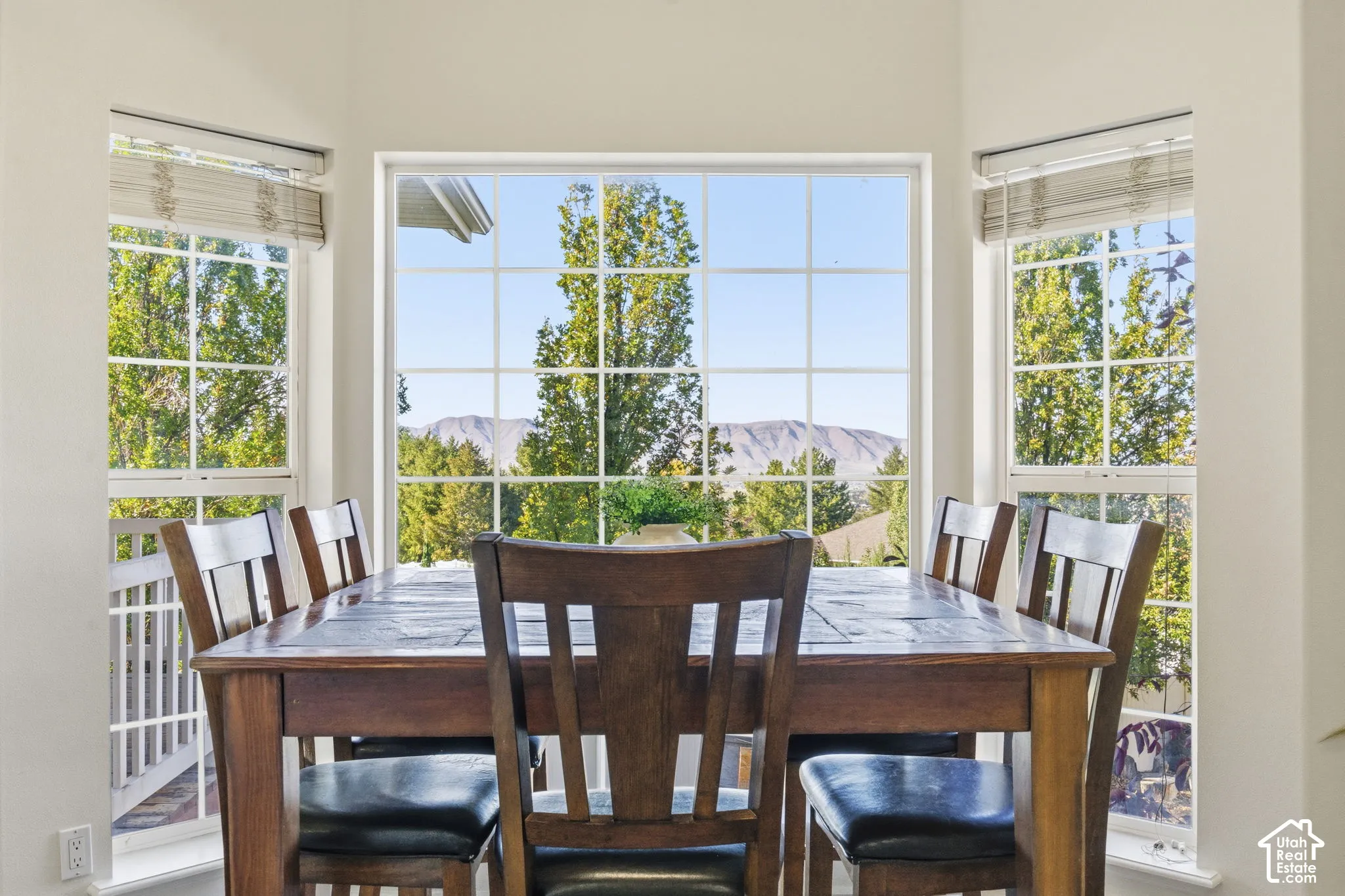 Bay window featuring grid-patterned glass, neutral wall finish, and natural scenery backdrop including mature trees and mountain topography