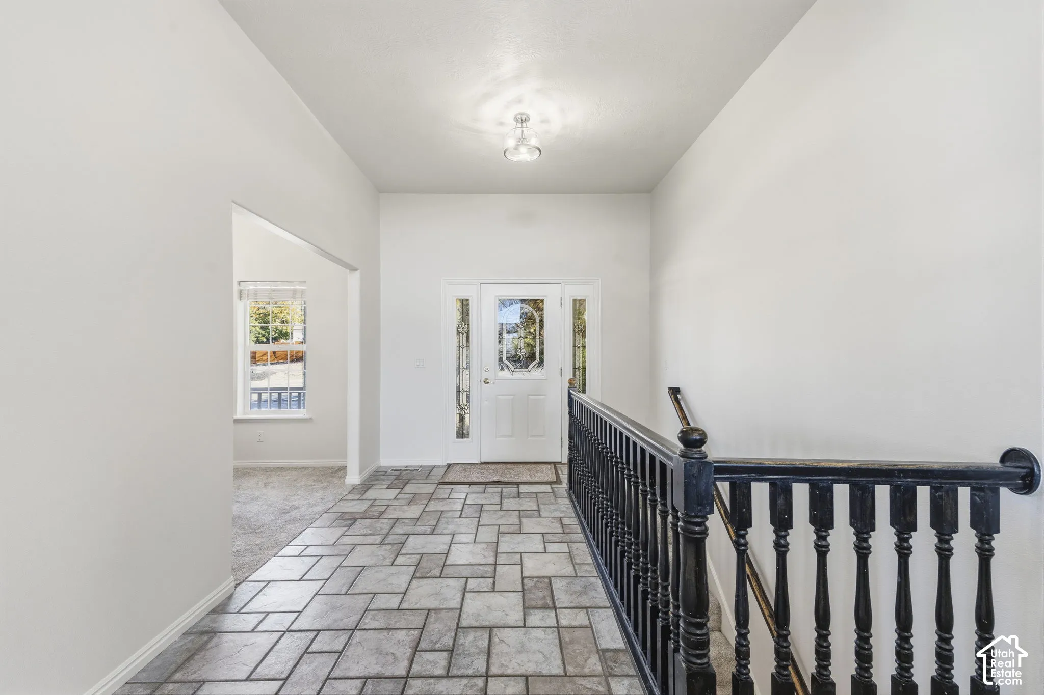 Entryway featuring tile flooring, a multi-pane glass entry door, and a black baluster railing with a wooden handrail