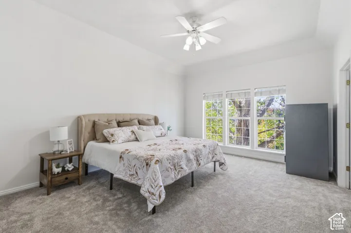 Tray ceiling, neutral carpeting, and a multi-light ceiling fan