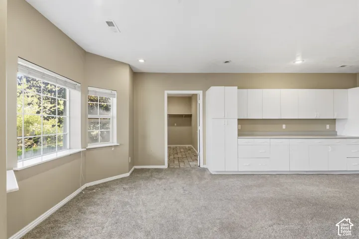 Expansive room featuring wall-to-wall carpeting, recessed lighting, white built-in cabinetry with extensive counter space, and windows with multi-pane glazing