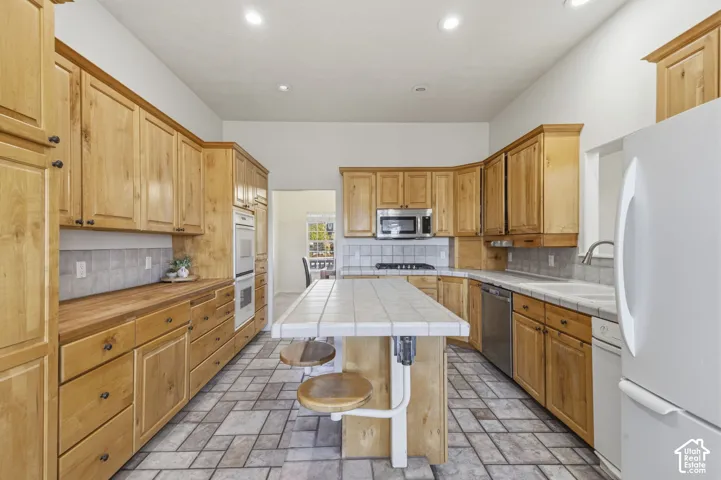 Kitchen featuring natural wood cabinetry, tiled island countertop, tile flooring, built-in double oven, and recessed lighting