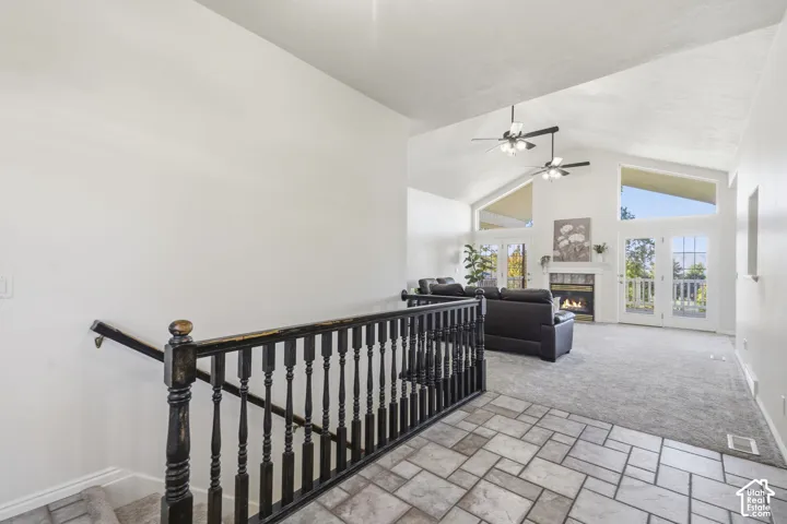 Vaulted ceilings, fireplace with tile surround, black spindle stair railing, ceiling fans, and large paneled windows