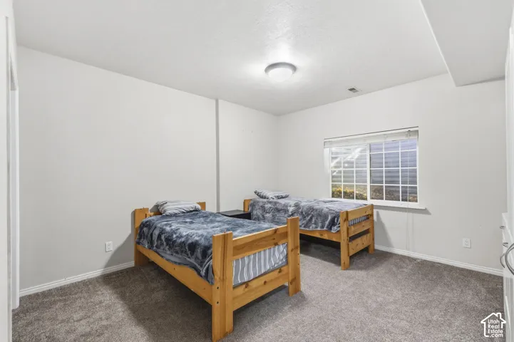 Room featuring neutral wall tones, gray carpeting, a single ceiling-mounted flush light fixture, and a large sliding window with blinds