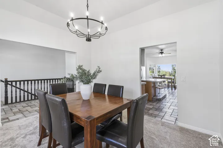 High-ceiling area featuring a black metal chandelier, dark wood-tone banister with spindles, and tile flooring