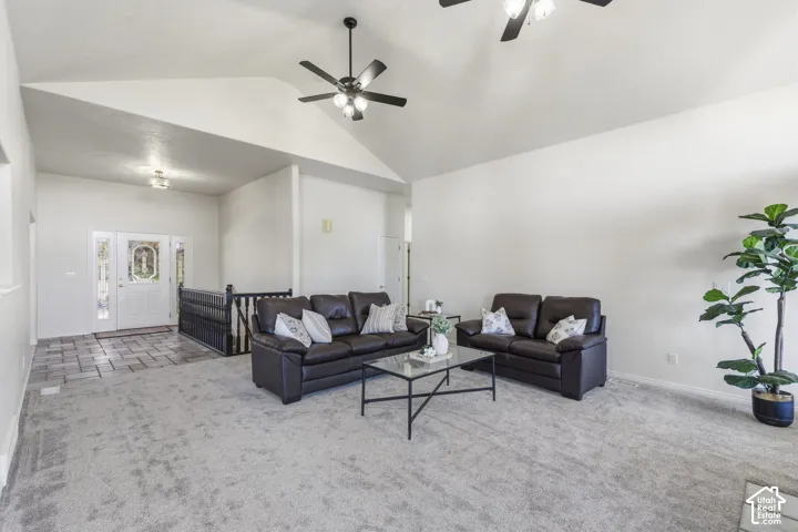 Vaulted ceilings, neutral carpeting, tiled entryway, wrought iron staircase railing, and dual ceiling fans