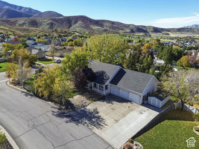 Single-story residence featuring a shingled roof, three-car garage, concrete driveway, and a detached storage shed