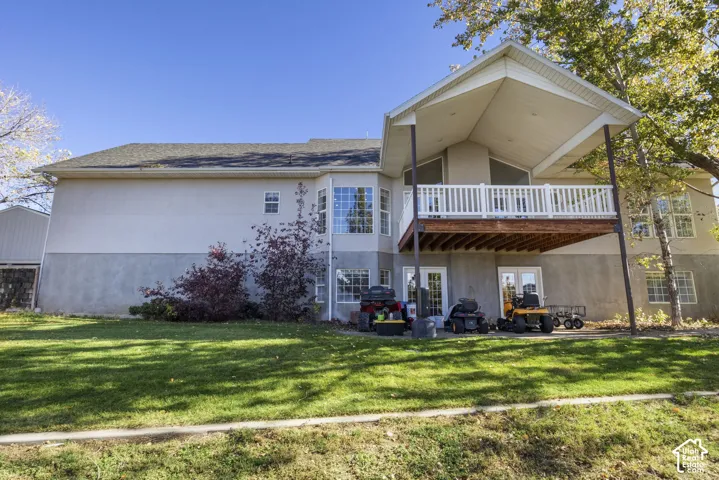 Rear exterior featuring a covered elevated deck with white railing, multi-pane windows, and a concrete patio area