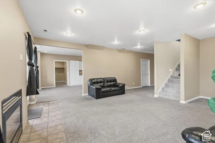 Interior space featuring recessed lighting, a built-in fireplace with a tile hearth, wall-to-wall carpeting, and a staircase with a handrail