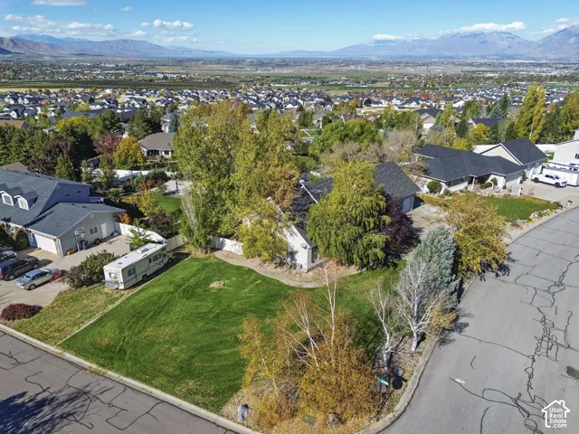 Corner lot featuring an expansive lawn, mature trees, and mountainous terrain in the distance