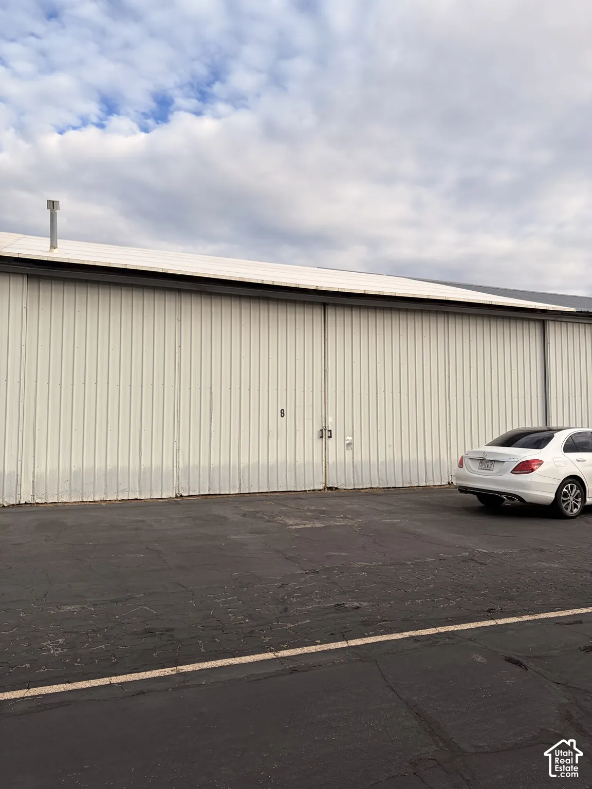 Industrial-style exterior with corrugated metal siding, large sliding hangar-style doors, and paved asphalt surface