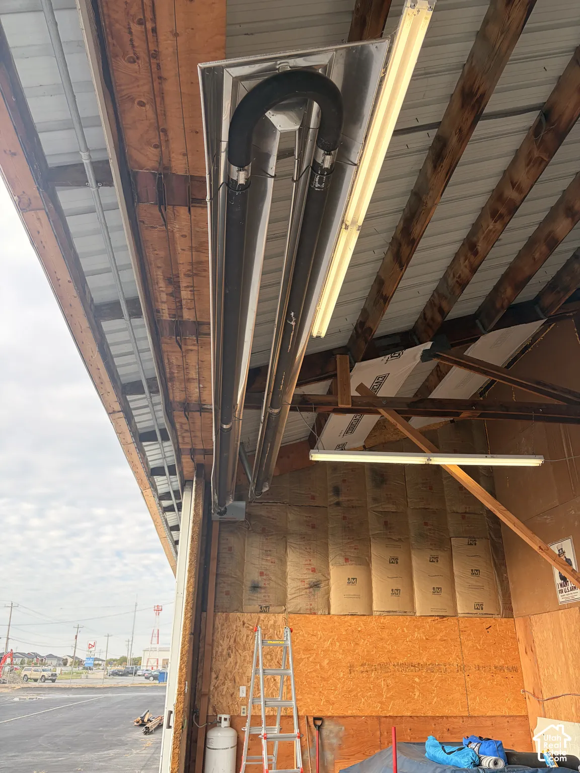 Ceiling-mounted infrared tube heater, exposed timber framing, and fluorescent shop lighting