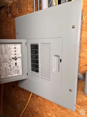 Electrical service panel with labeled circuit breaker directory, mounted on oriented strand board wall sheathing