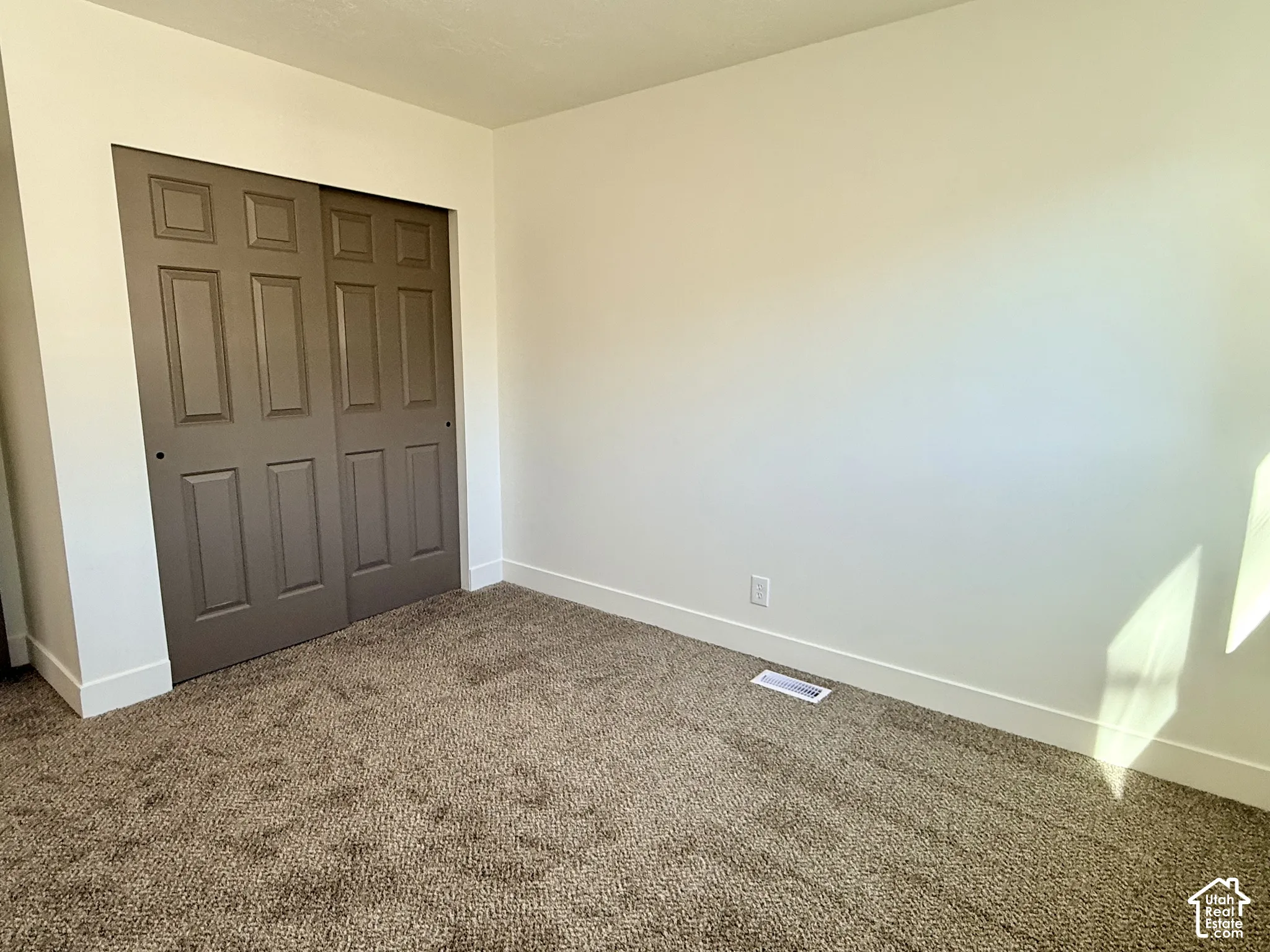 Neutral-toned carpeted flooring and a built-in closet featuring two six-panel sliding doors