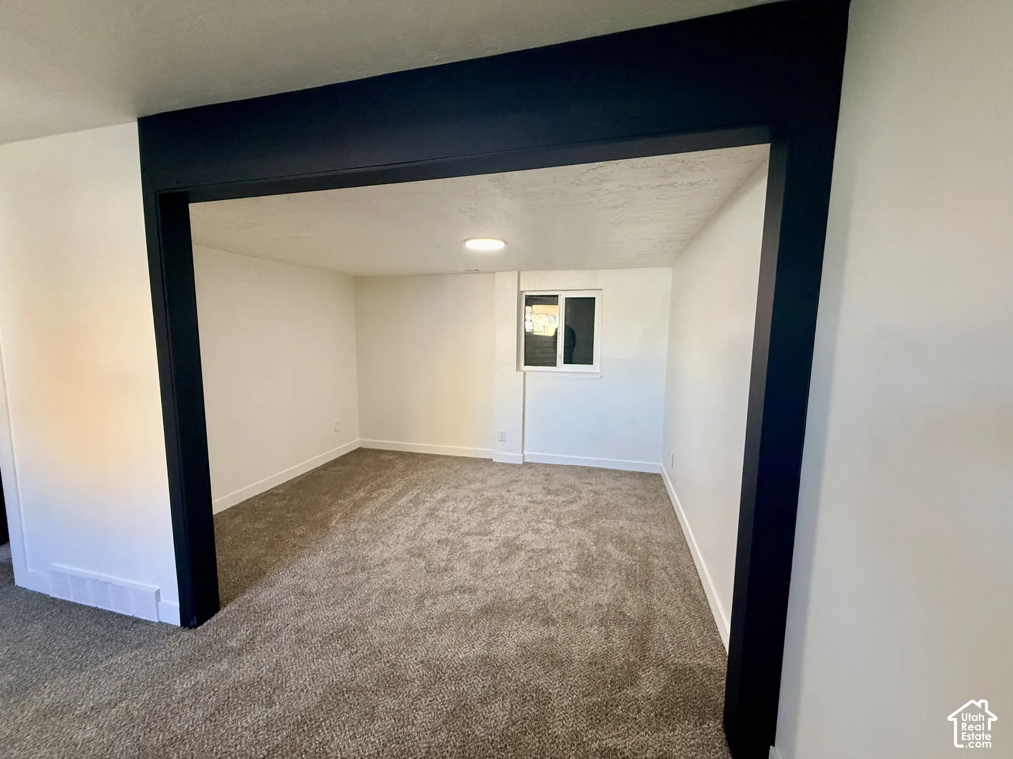 Neutral interior space featuring carpeting, recessed lighting, and a dark-framed structural opening