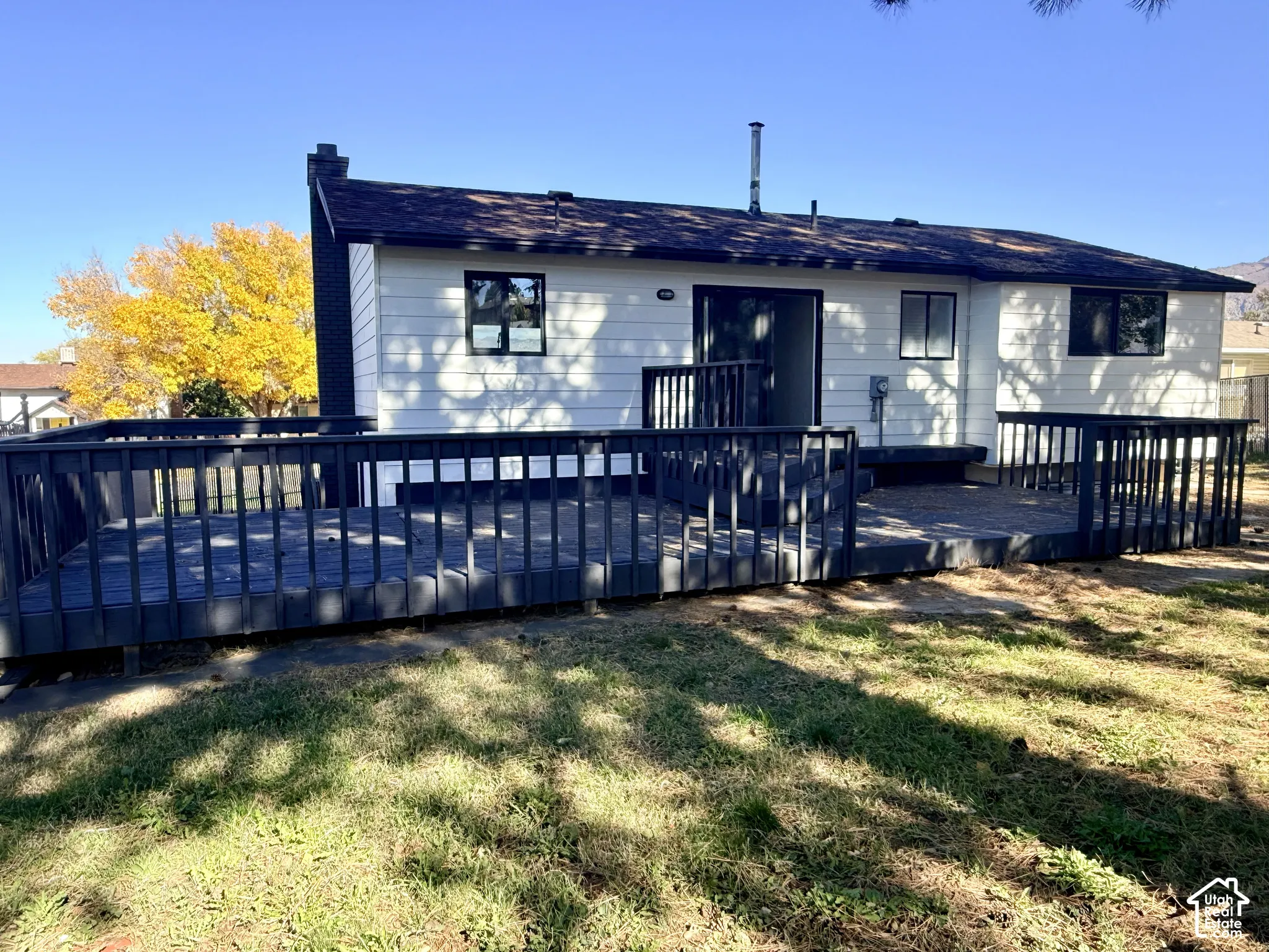 Exterior with horizontal siding, dark-toned wood deck with perimeter railing, and chimney