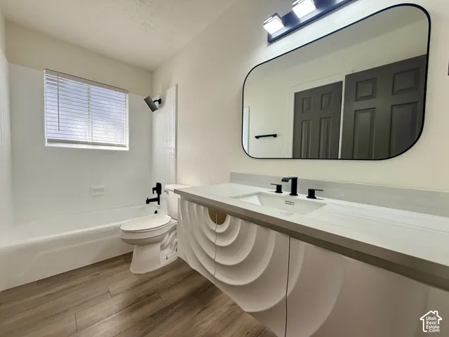 Bathroom featuring a wall-mounted floating vanity with geometric textured cabinetry, white surface countertop, undermount sink, and matte black fixtures