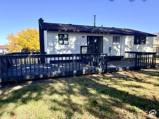 Exterior with horizontal siding, dark-toned wood deck with perimeter railing, and chimney