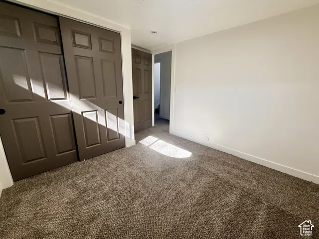 Neutral interior space featuring neutral wall paint, textured wall-to-wall carpeting, and sliding panel doors with recessed panels