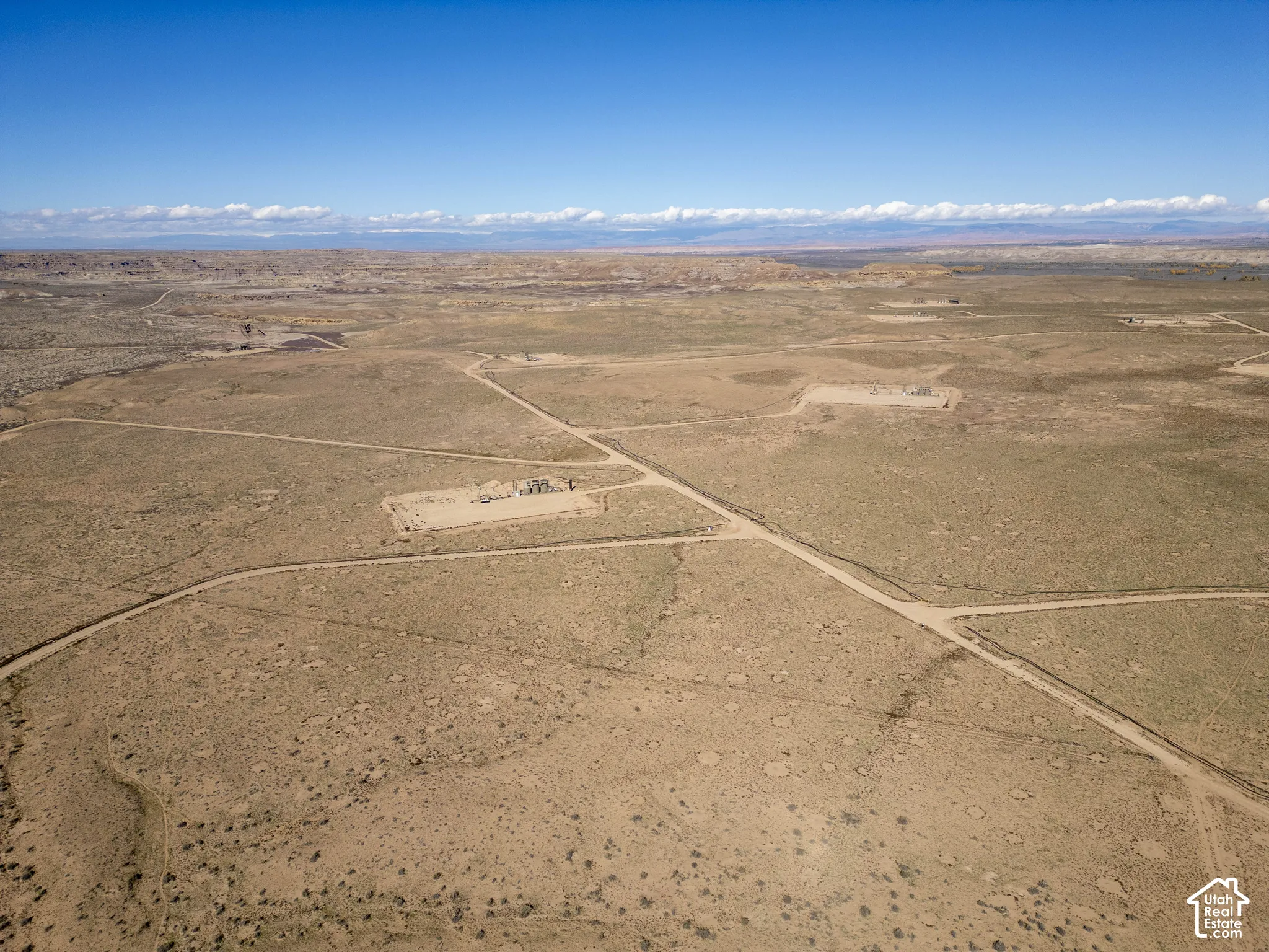 Expansive desert parcel featuring leveled building pads, graded dirt access roads, and mountain backdrop