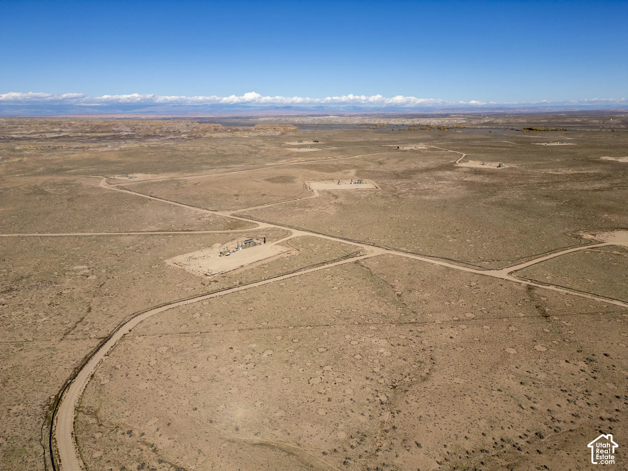 Expansive parcel of desert land featuring dirt access roads, native vegetation, and mountain silhouettes