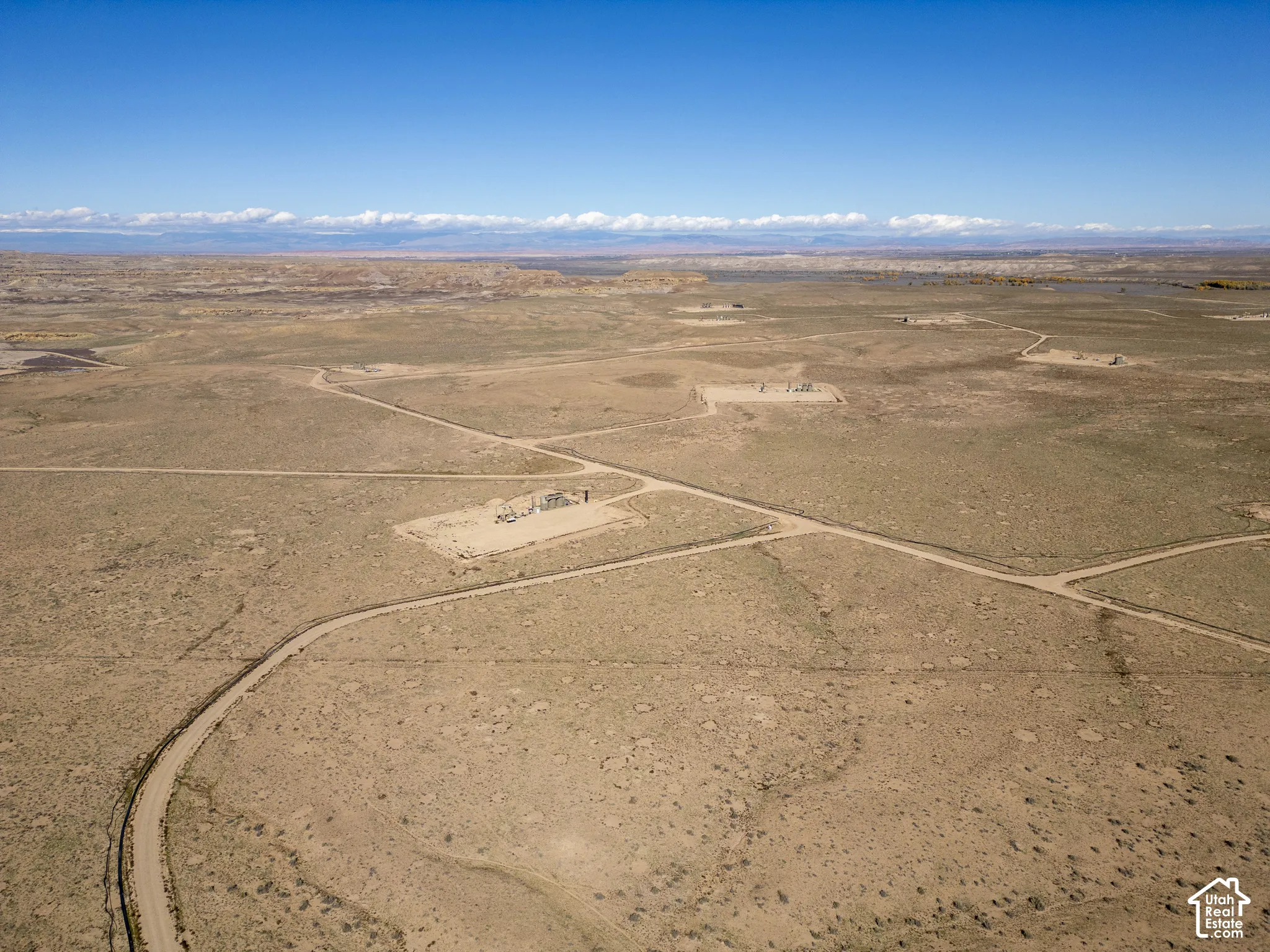 Expansive acreage featuring rugged desert topography, unpaved road access, and distant mountain range silhouettes