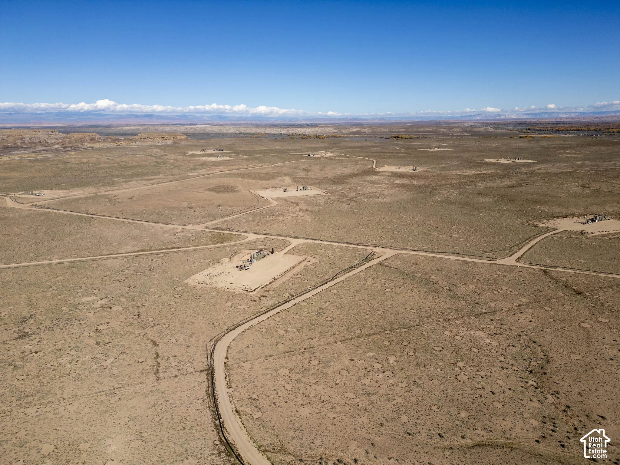 Expansive desert acreage featuring natural terrain, dirt access paths, and distant mountain backdrops