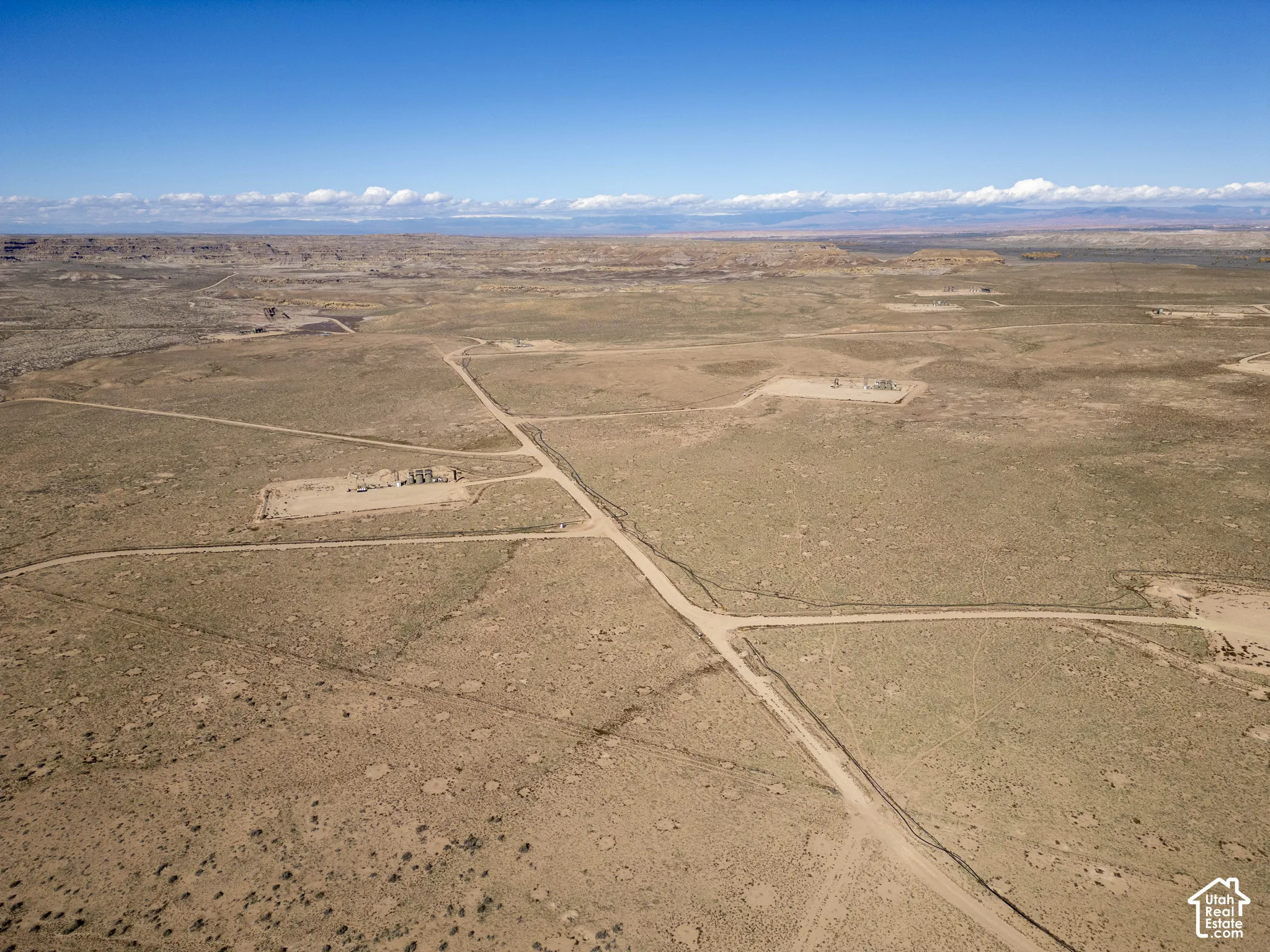Expansive desert acreage featuring natural terrain, dirt-surface access roads, and distant mountain topography