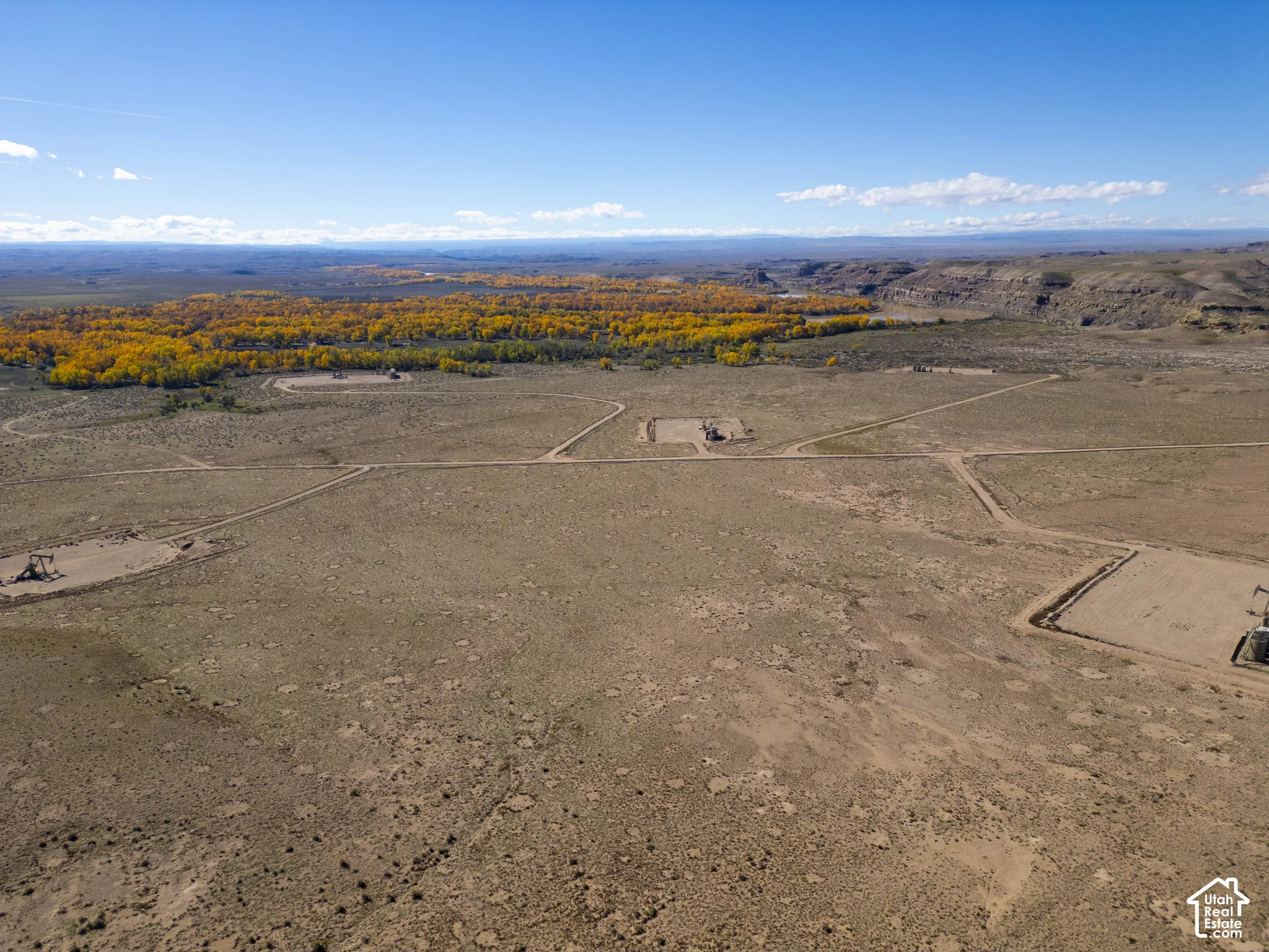Expansive acreage featuring rugged desert terrain, established dirt access paths, and mature cottonwood trees