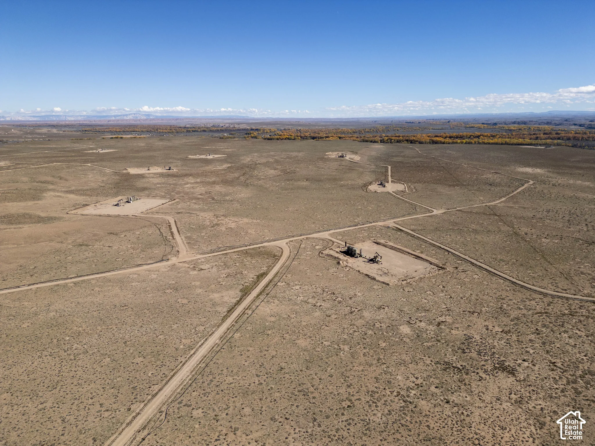 Expansive desert acreage featuring established dirt access roads and industrial infrastructure