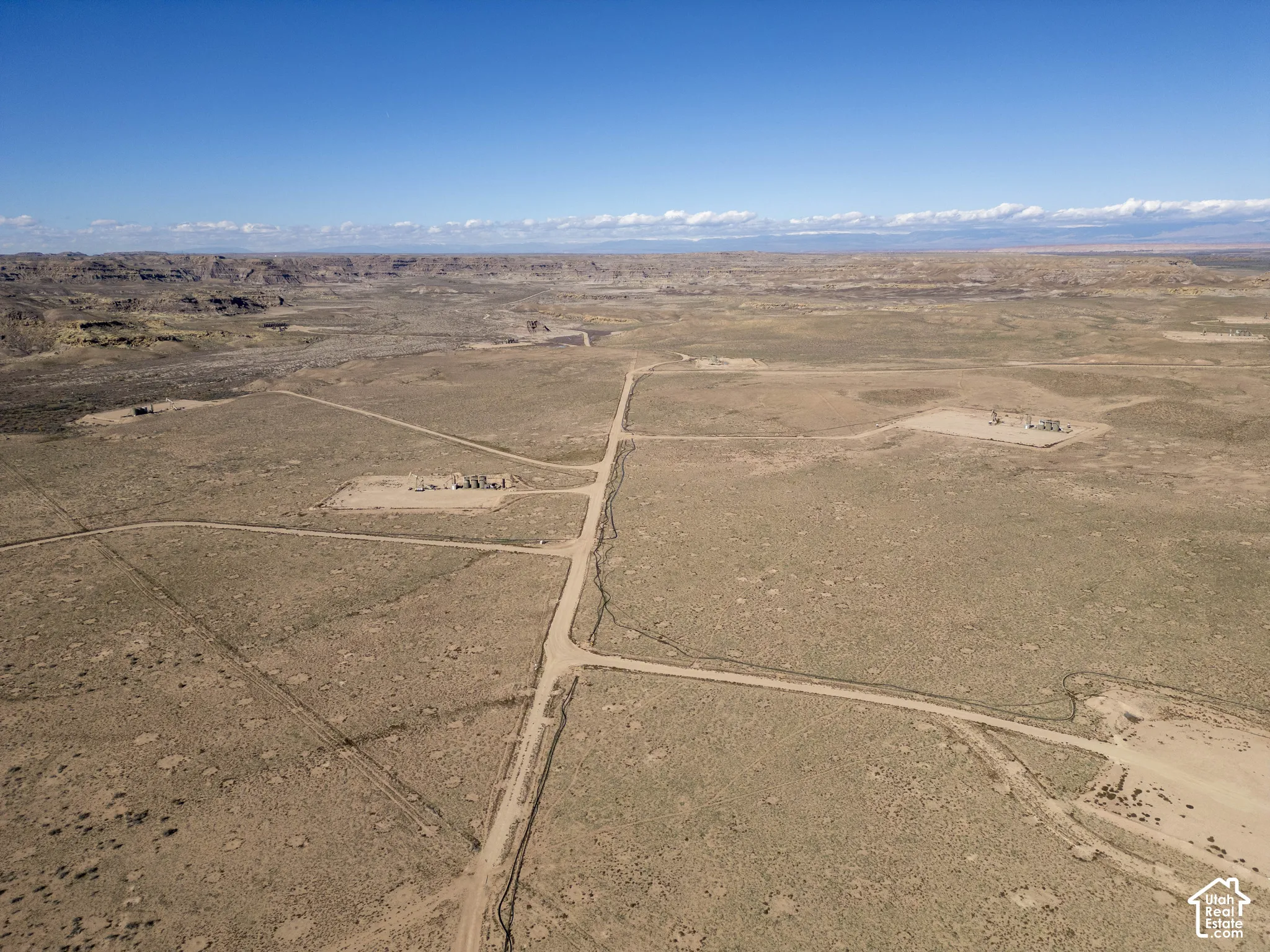 Aerial perspective of expansive high-desert acreage featuring unpaved roadways and open terrain with a mountain backdrop