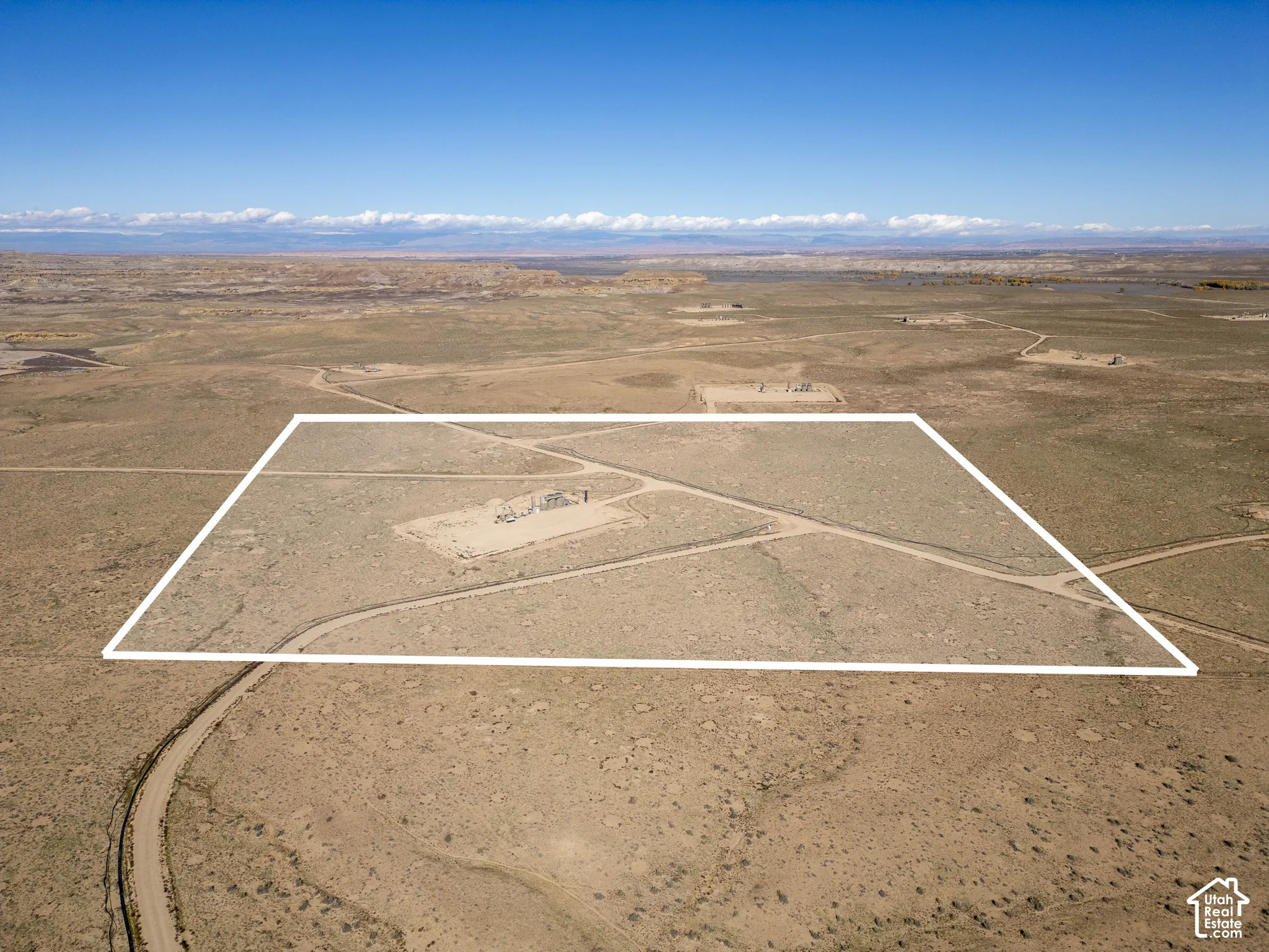 Expansive acreage featuring native desert terrain, dirt-surface access roads, and mountain range backdrop