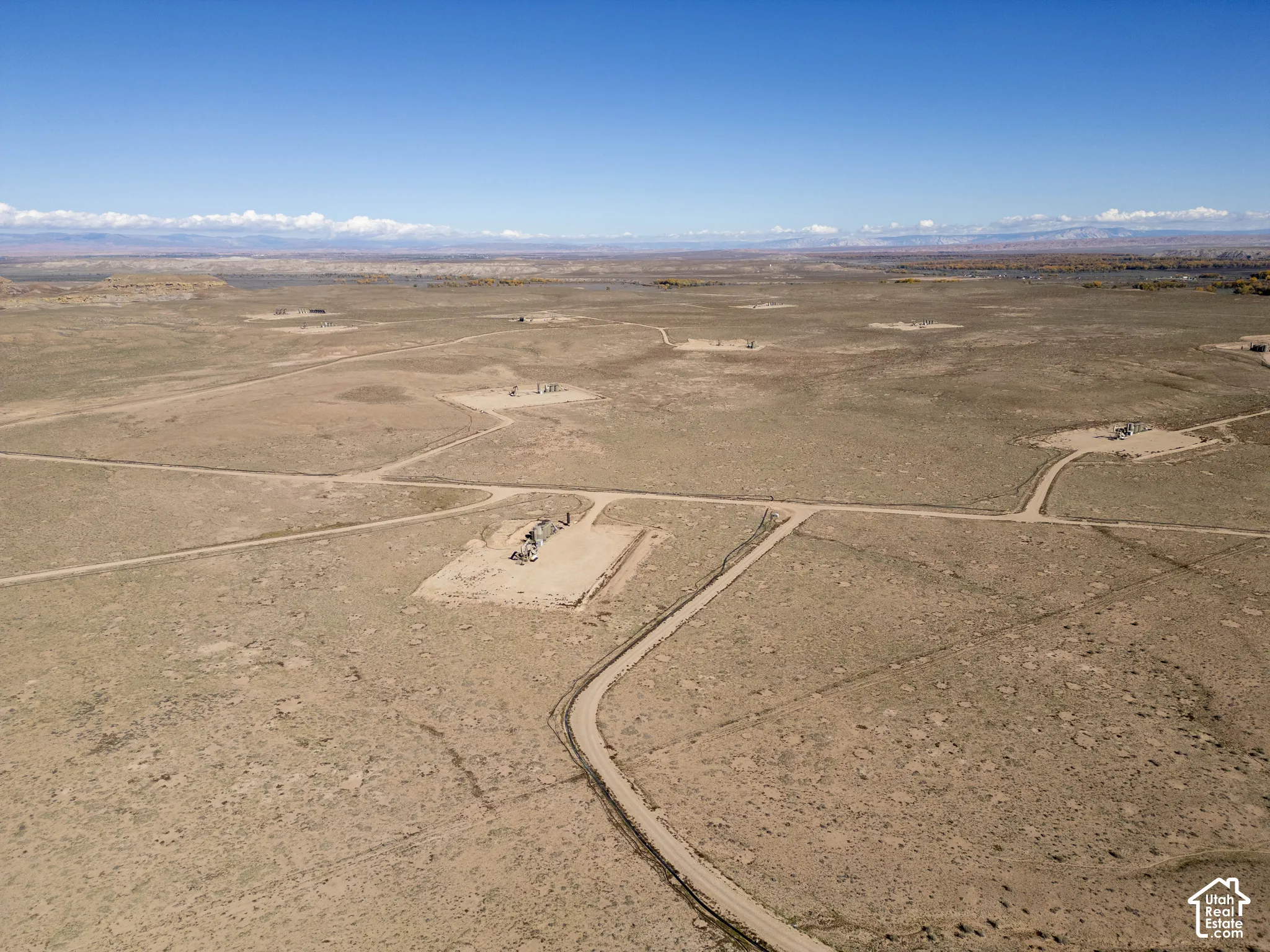 Expansive desert acreage featuring natural terrain, dirt-surface access roads, and mountain-range backdrops