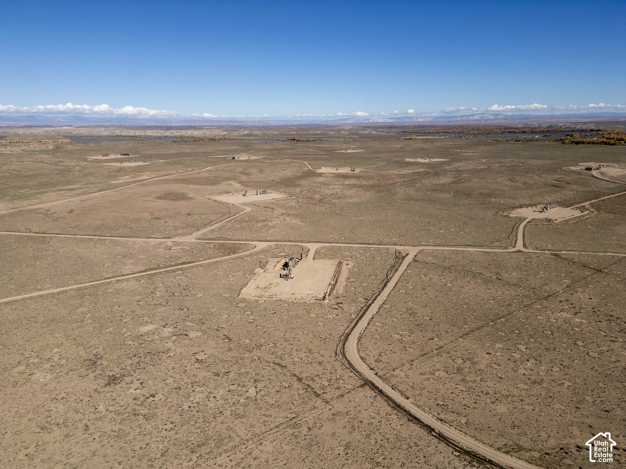 Expansive desert acreage featuring native scrub brush, unpaved access paths, and distant mountain range terrain
