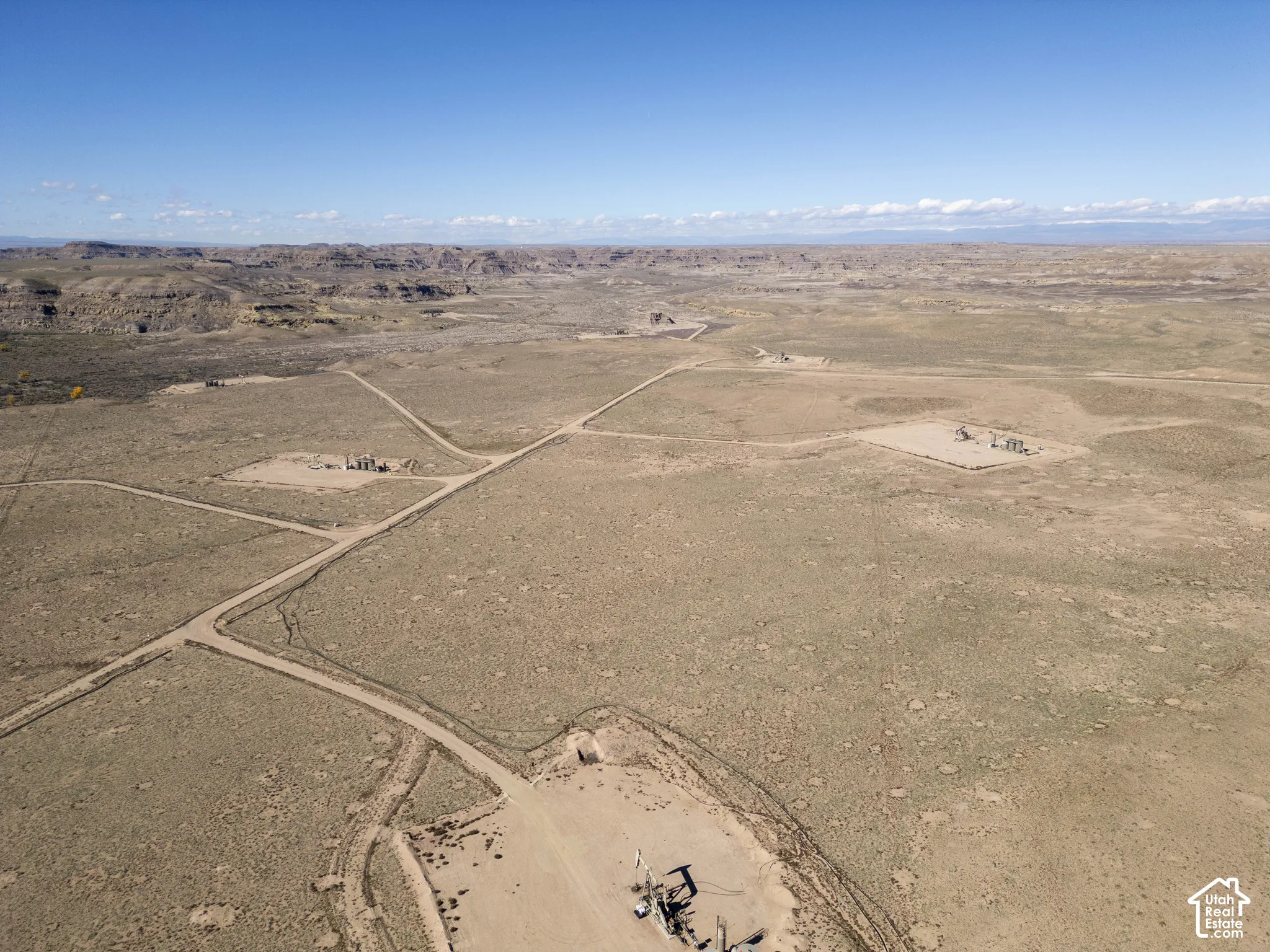 Expansive desert acreage featuring established dirt access roads, prominent ridgeline horizons, and open terrain