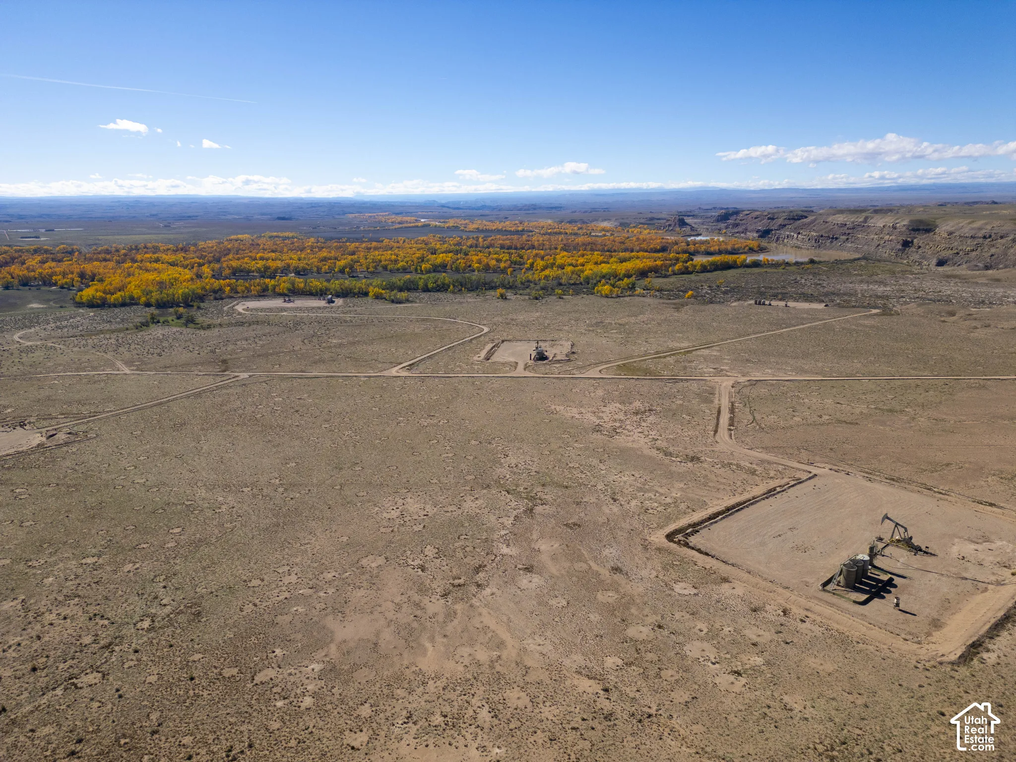 Expansive desert acreage featuring natural vegetation, established dirt access roads, and multiple oil extraction pump jacks