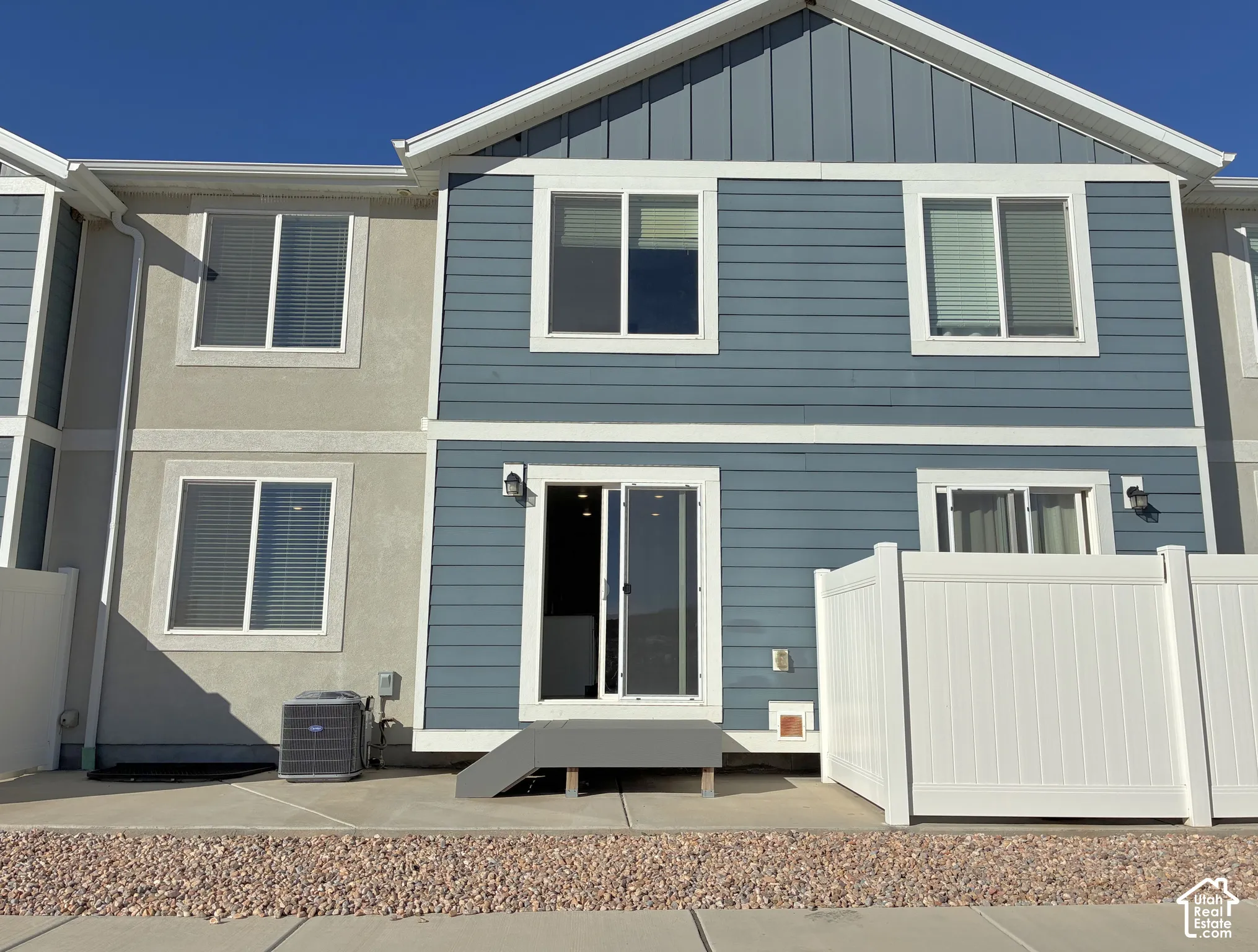 Backside Exterior facade featuring multi-tone siding, a concrete patio, a private vinyl privacy fence, and sliding glass door access