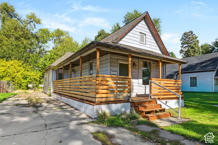 Single-story exterior featuring horizontal siding, a gabled roofline, and a covered front porch with horizontal wood-slat railings