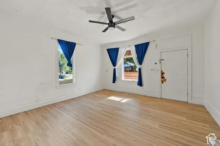 Interior space featuring wood-finish flooring, two windows with white trim, and a ceiling-mounted matte black fan