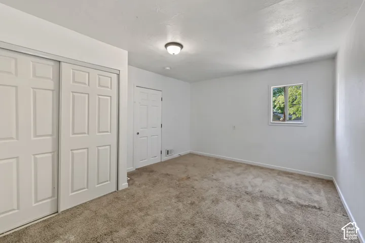 Interior space featuring carpeting, a sliding dual-panel closet door, a single-panel interior door, and a flush-mount ceiling light fixture