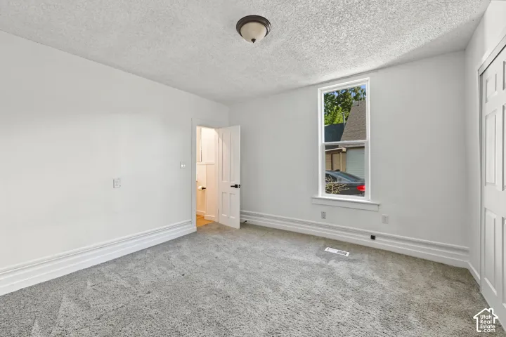 Neutral-toned wall-to-wall carpeting, single-hung window with exterior casing, white multi-panel interior door, and semi-flush mount ceiling lighting