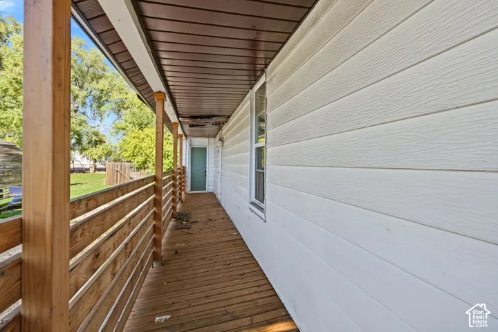 Covered porch featuring horizontal wood-slat railing, wooden deck flooring, and white horizontal siding