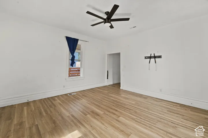 Interior space featuring wood-finish flooring, a matte black multi-blade ceiling fan, and a neutral wall finish