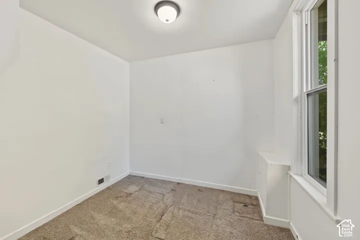 Neutral-toned interior space featuring carpeting, a double-hung window, and built-in cabinet storage