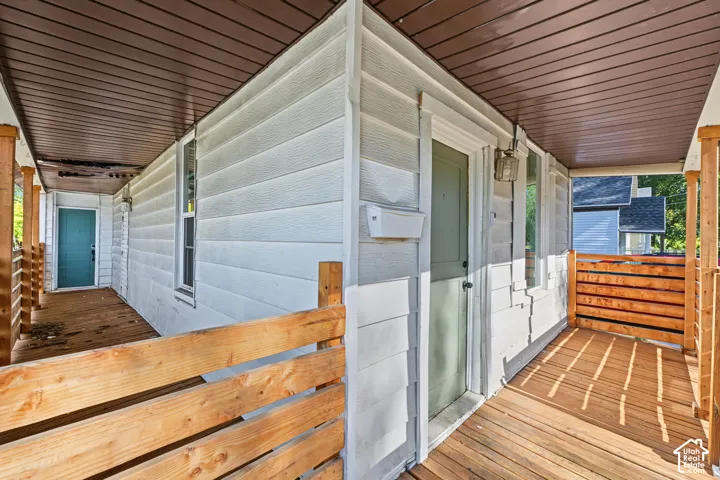 Covered wrap-around porch featuring wood-finish decking, horizontal wood-slat railings, and an integrated ceiling soffit