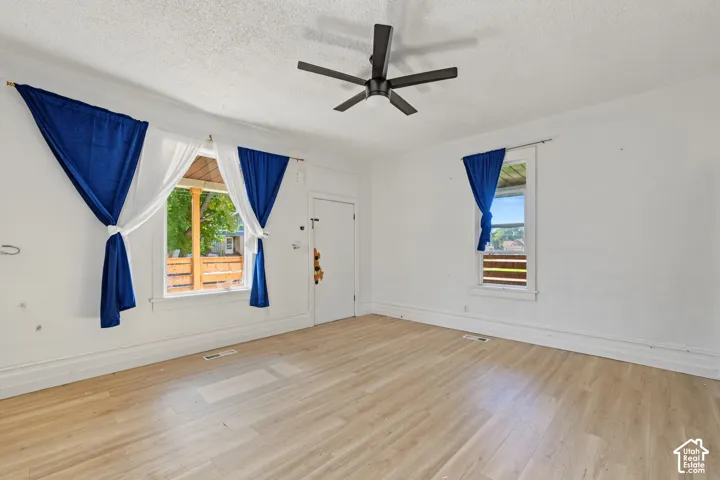 Interior space featuring wood-finish flooring, two large windows with casing, and a ceiling-mounted matte black fan