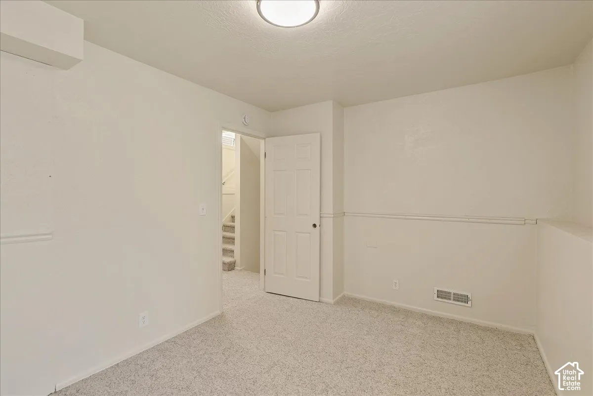 Neutral-toned interior space featuring wall-to-wall carpeting, chair rail molding, and a six-panel interior door