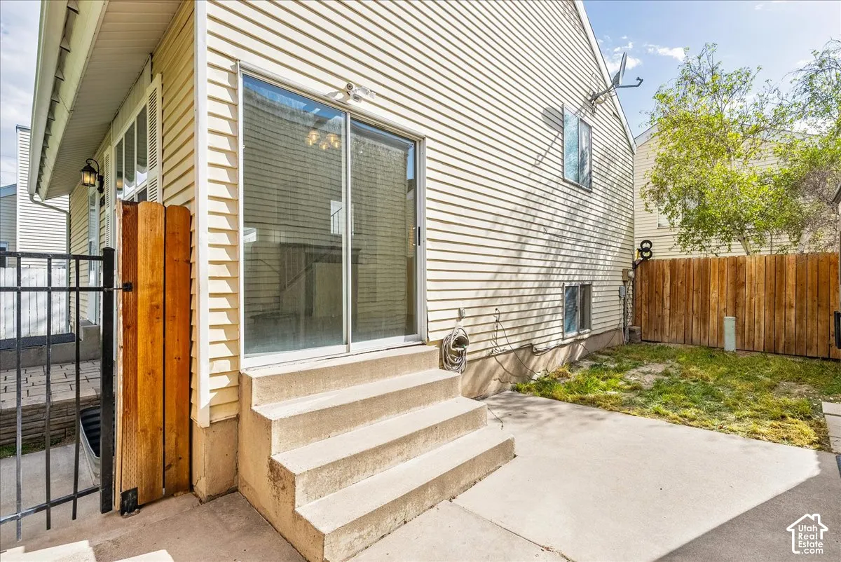 Exterior featuring horizontal vinyl siding, concrete patio, sliding glass door, tiered concrete steps, and wood fencing