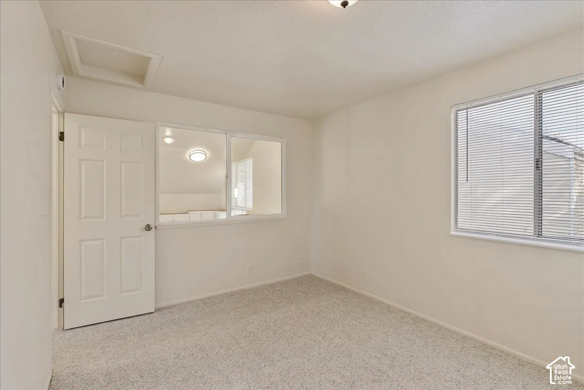 Room with neutral carpeting, six-panel interior door, inset ceiling lighting, and a large horizontal interior window